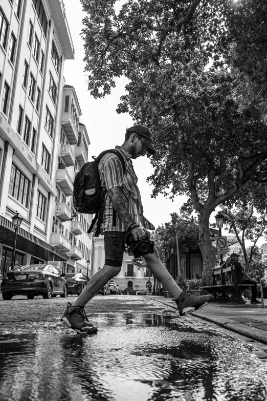 a man walking down the street in the rain carrying his purse