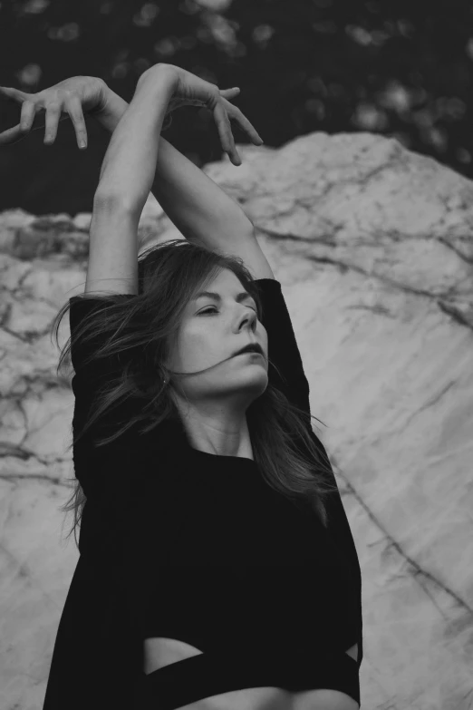 the woman is posing with her arms stretched out in a rock formation