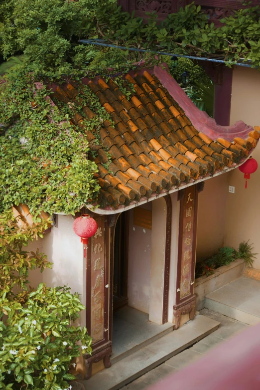 an old chinese building with red lanterns and ivy on it