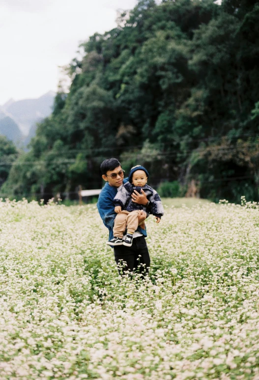 two s are holding a little boy in a field of flowers