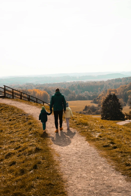 a man and two children are walking together on a dirt trail