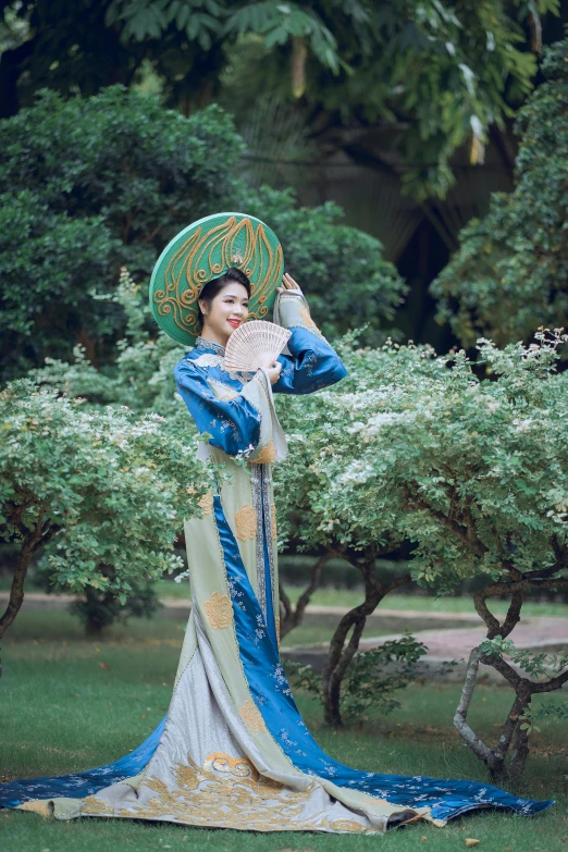 a woman standing in a grassy area next to a shrub