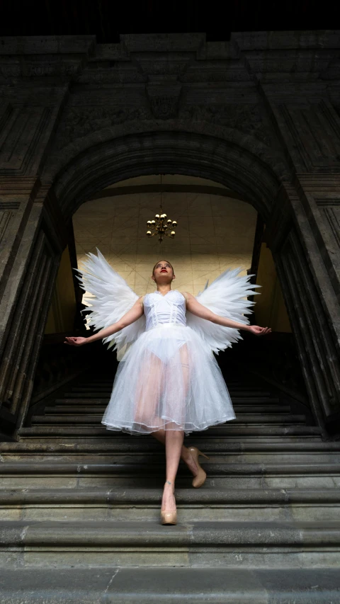 a woman in a white tutu is on steps in front of an archway