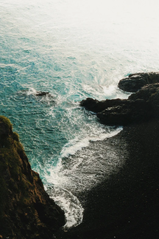 waves crashing into a rocky cliff as seen from a cliff