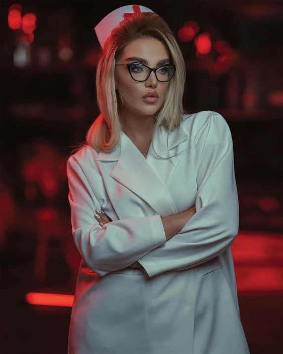 a woman in a white coat and glasses standing with her arms crossed