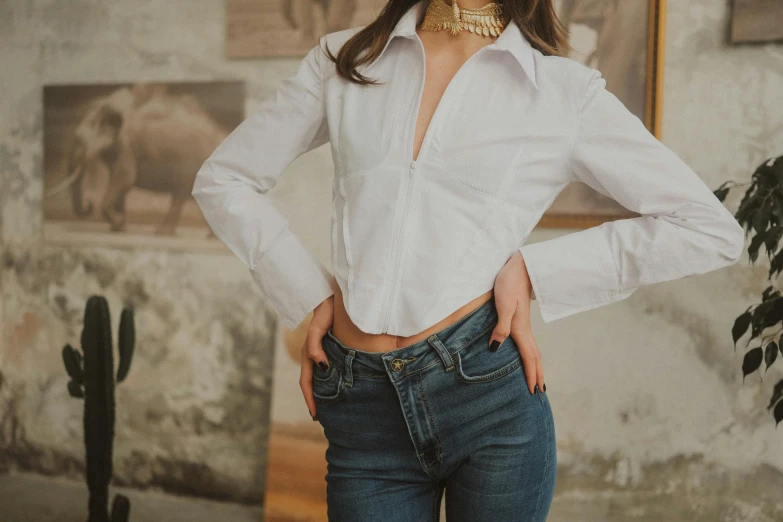 a woman posing in a white shirt and jeans