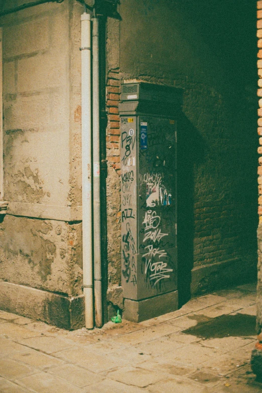 a box has graffiti on it and it is next to a brick building