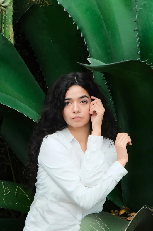 a young woman is posing in front of cactus leaves