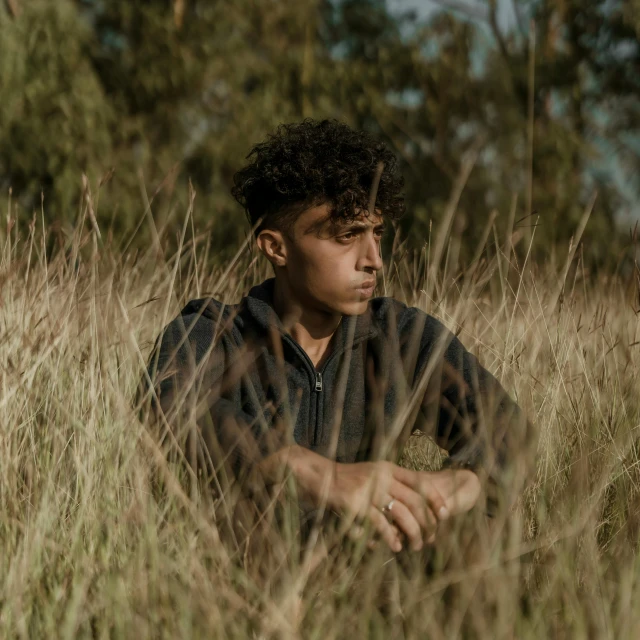 a  sitting in a tall grassy field