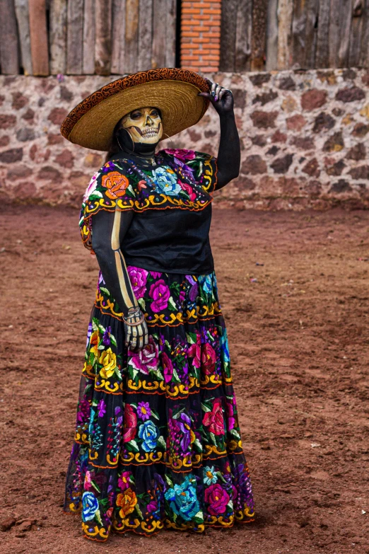 a woman in mexican dress standing in the dirt