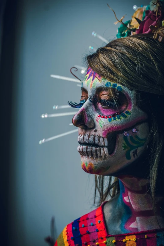 a woman is decorated with a multicolored mask and has painted on her face