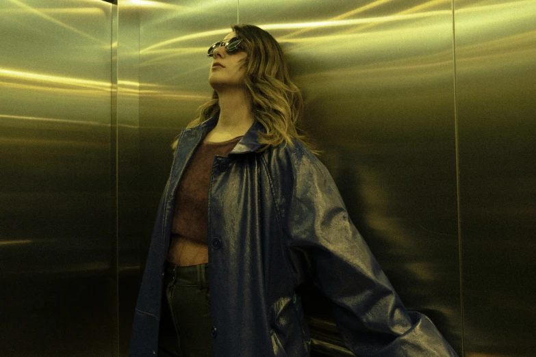 a person standing in an elevator wearing a blue coat