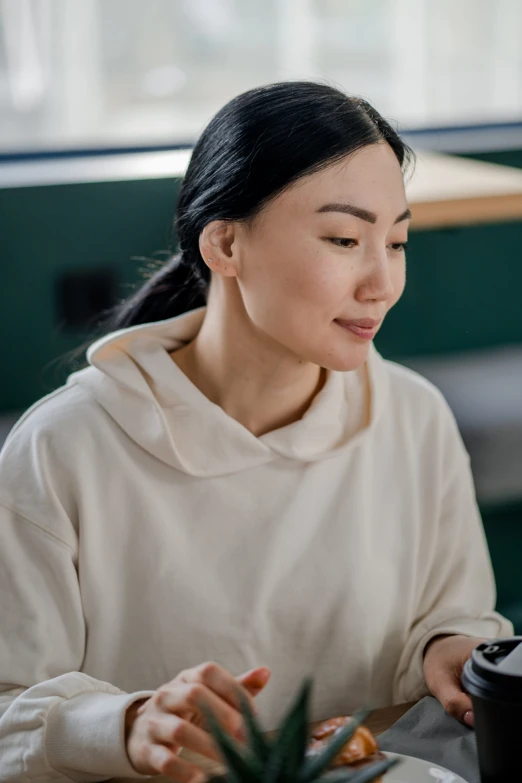 woman with black hair sitting at table with pineapple in background