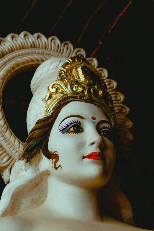 a white statue with gold paint and a black background