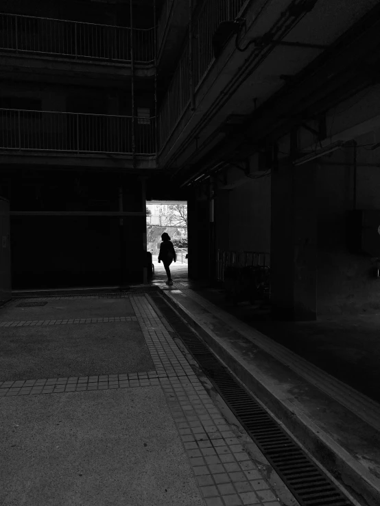 the lone person stands in an alley by a clock