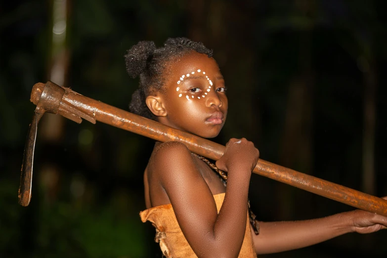 a girl wearing a brown dress holding a large wooden stick