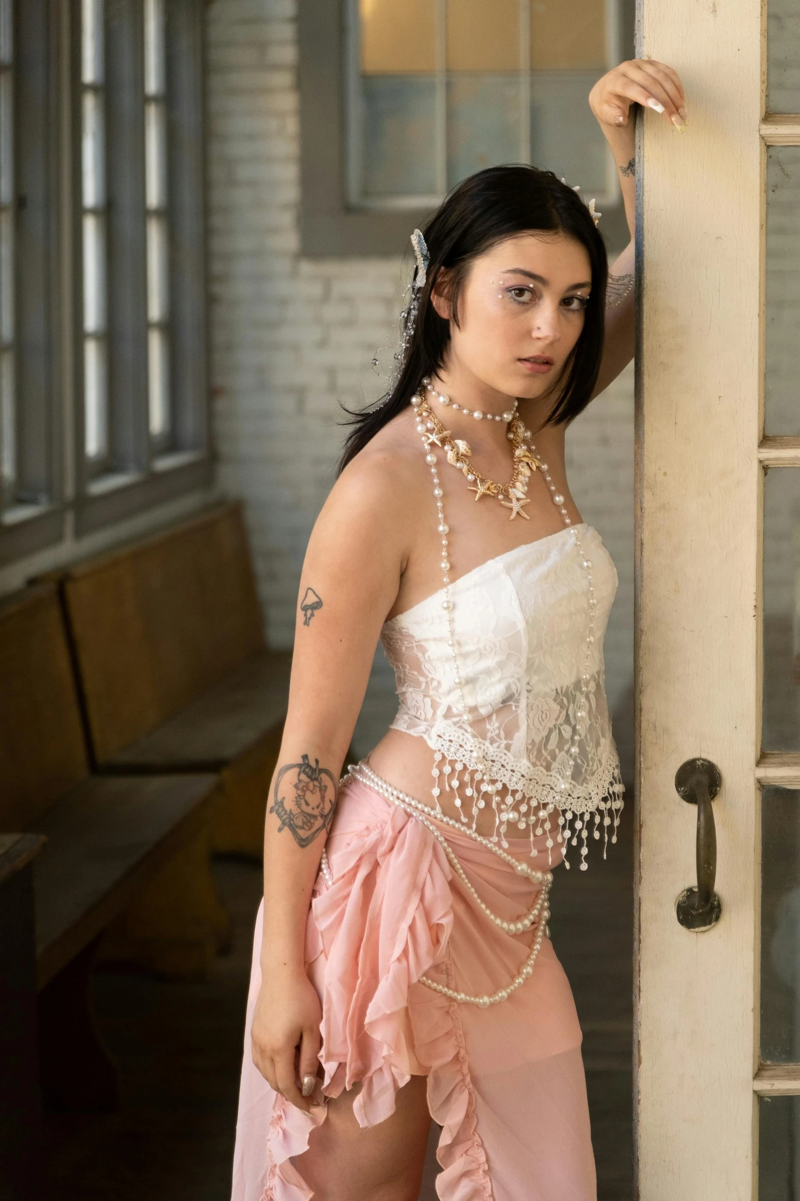 woman in white corset and pink dress posing with pearls