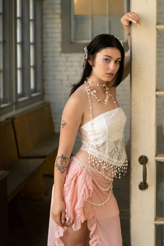 woman in white corset and pink dress posing with pearls