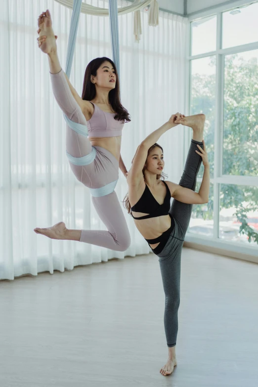 two women standing up in the air on one leg