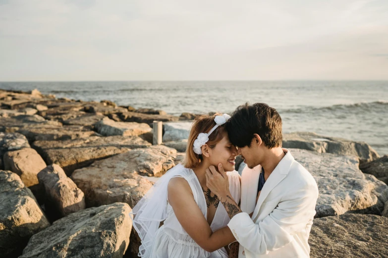 a young couple is sitting on a large rocky beach