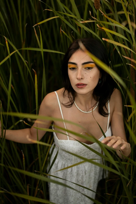 woman with artistic make - up and a white dress is standing in the tall grass