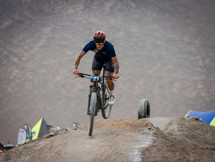 a man riding on top of a dirt hill with a helmet