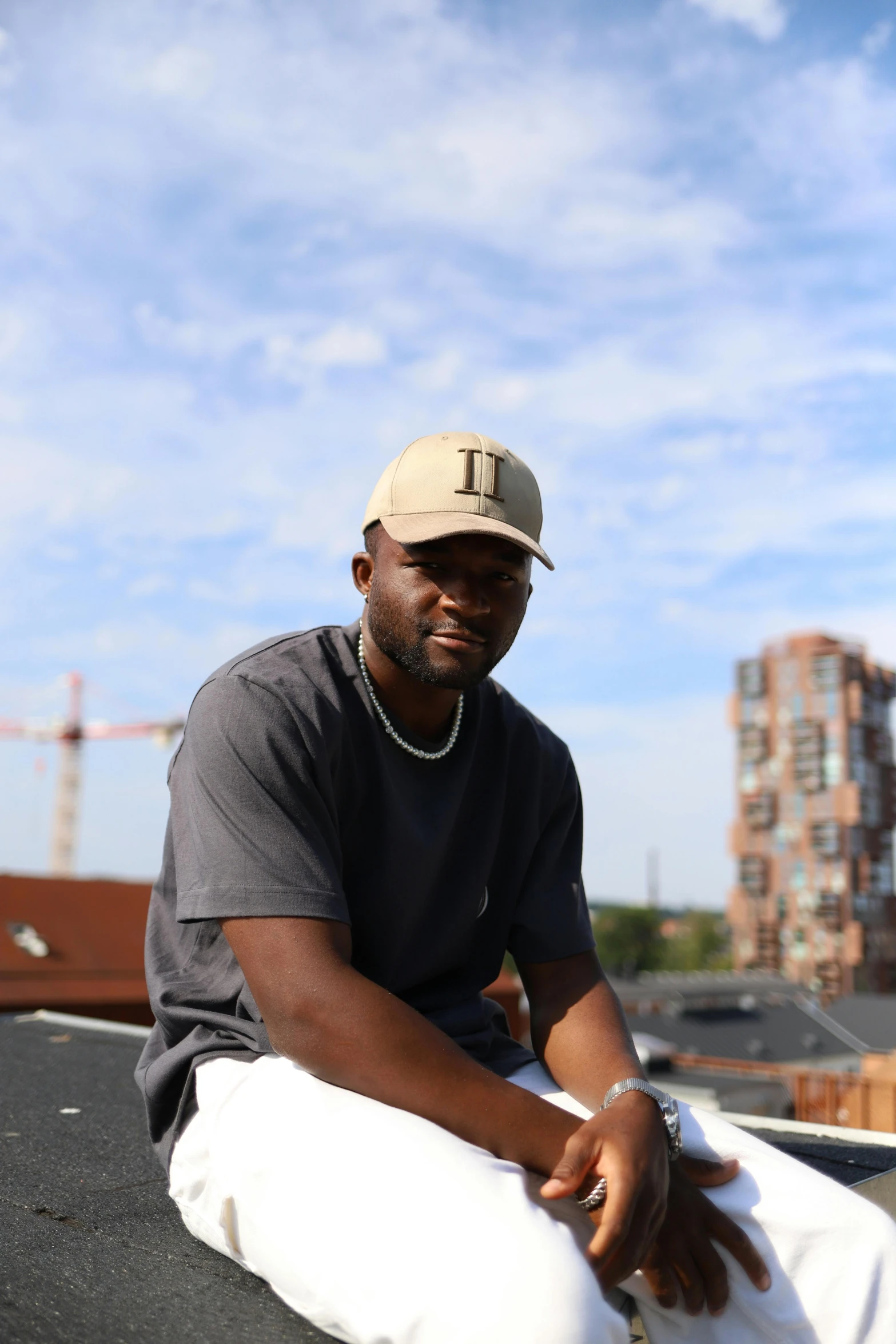 a man in grey shirt and khaki cap sitting on roof