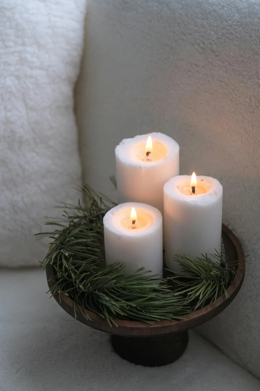 a set of three white candles on a tray