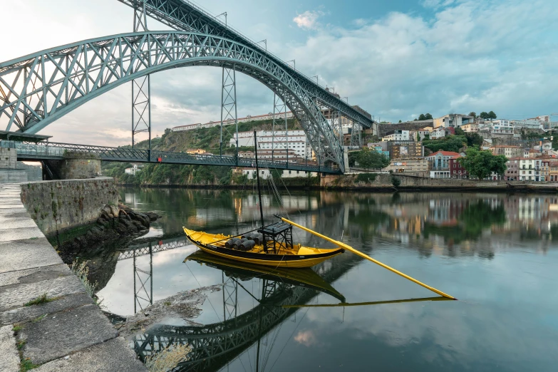 a yellow kayak on the water under an iron bridge