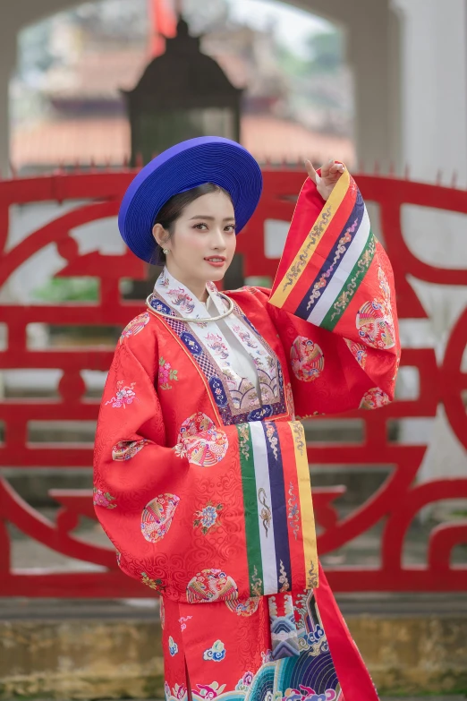 a woman in an oriental outfit is holding up a fan