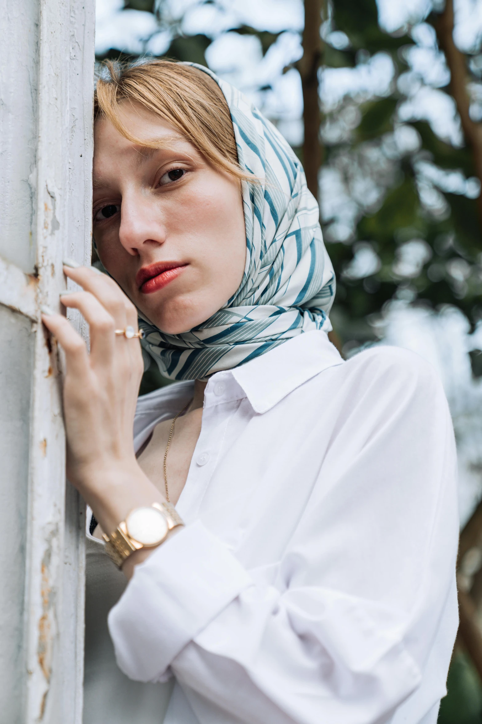 a woman standing next to a white wall looking through a window