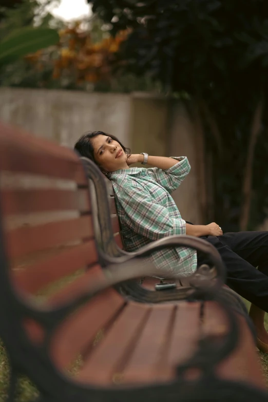 a woman leaning against the back of a bench