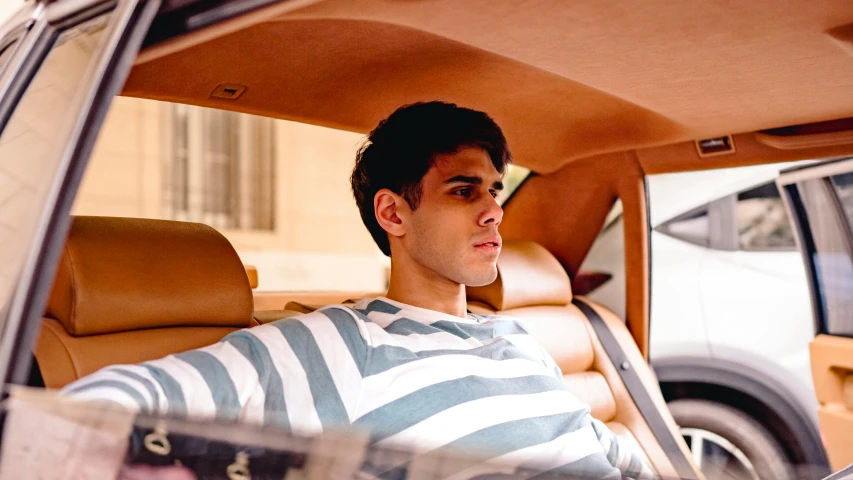 a man sitting in a car with a striped shirt