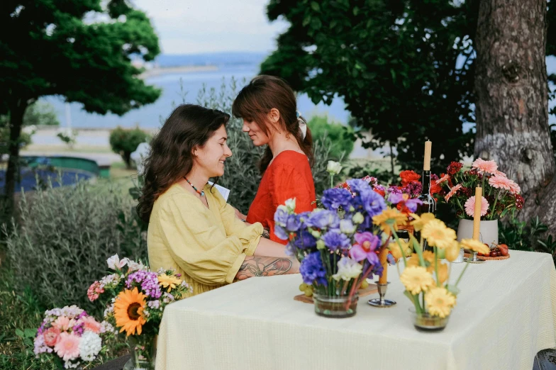 two young women are sitting at a table and talking