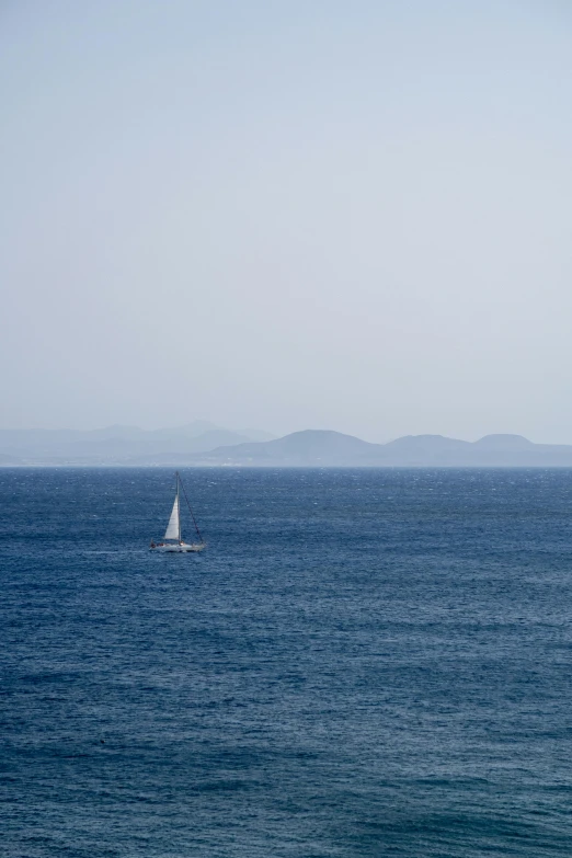 the sailboat floats close to the shore in the ocean