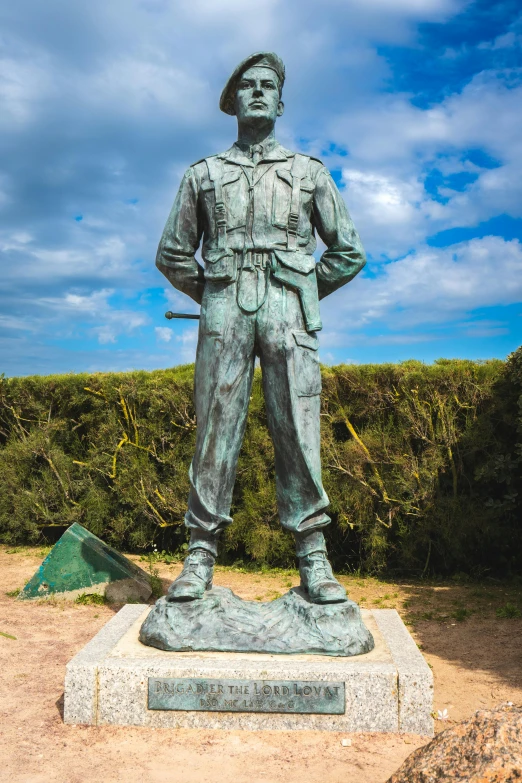 a large bronze statue of a soldier is located on the side of the road