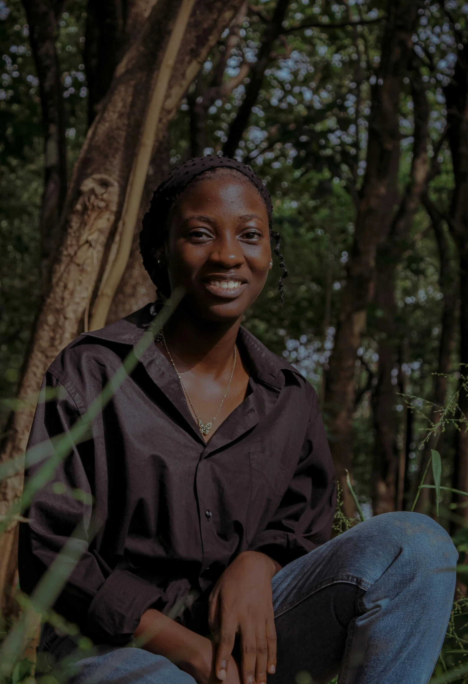 a woman sitting on the ground in a forest