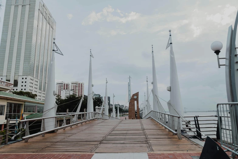 a metal bridge with wooden posts leading to two tall buildings