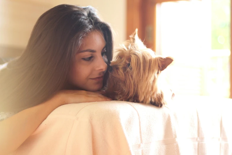 a girl with a dog on her shoulder while sitting next to the couch