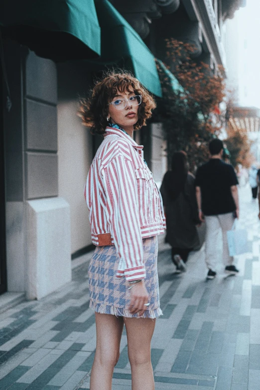 woman posing on city sidewalk, with red and white shirt over top