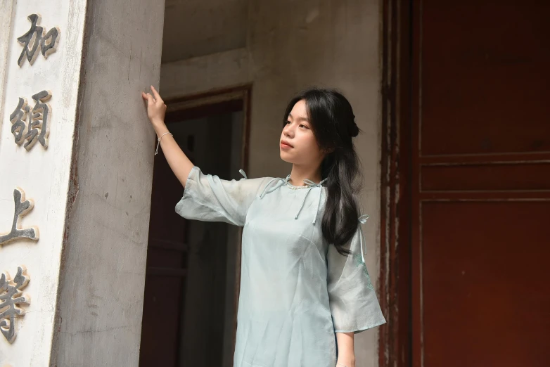 a young asian woman stands by a wall