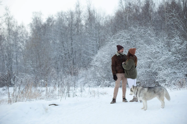 a couple and their dog are walking in the snow