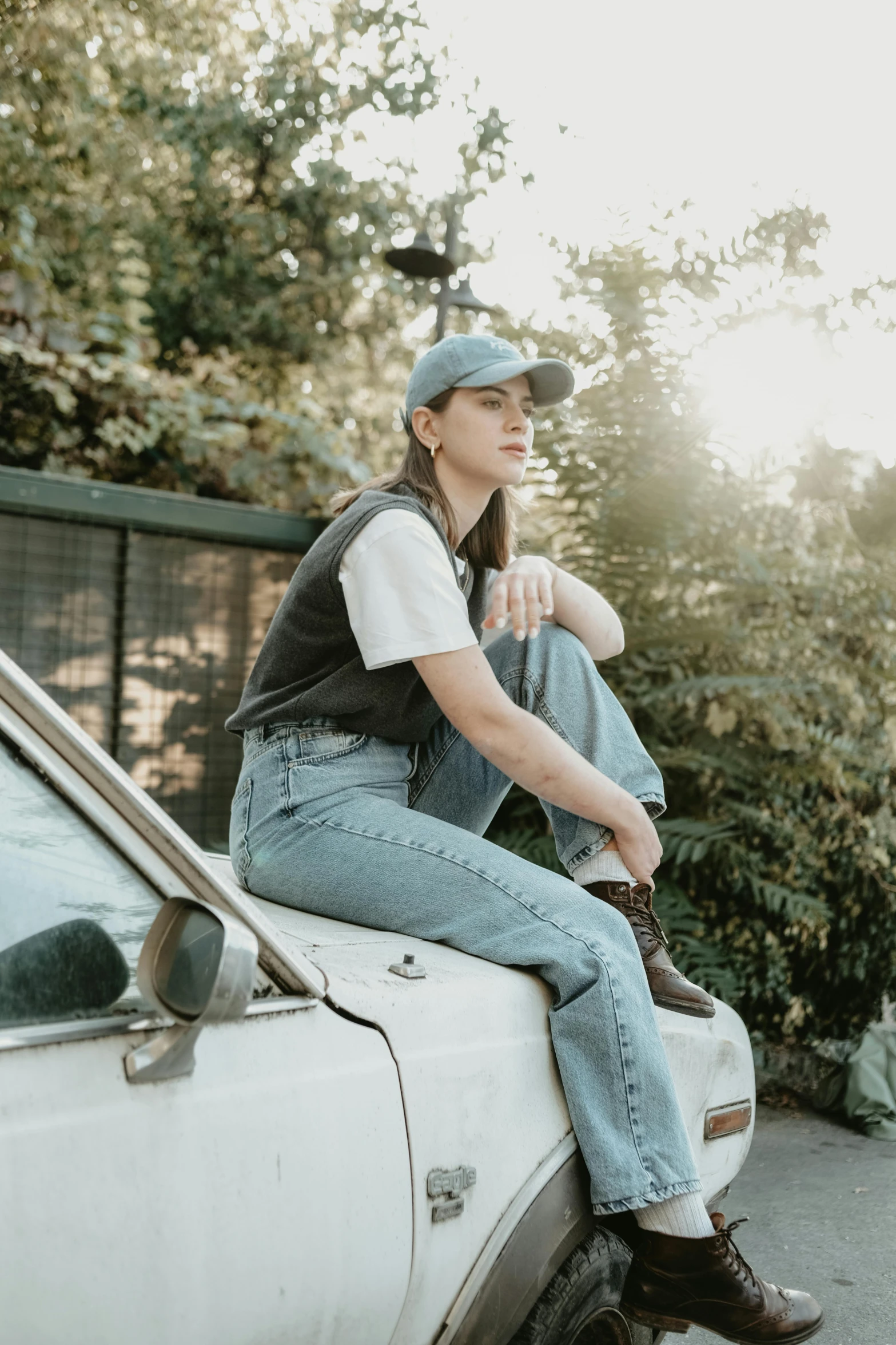 a woman sits on the hood of a car