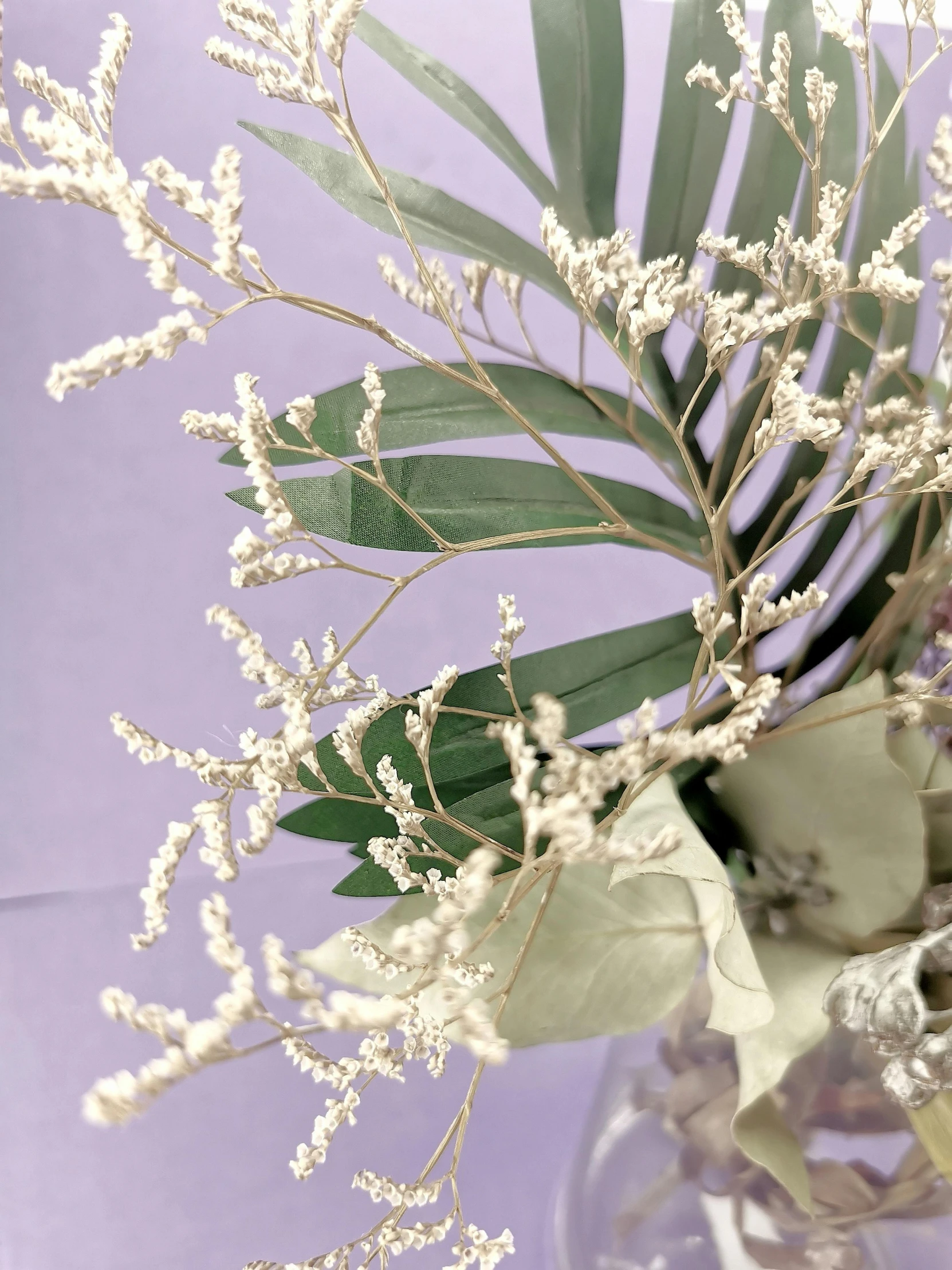 a vase filled with green leaves and white flowers