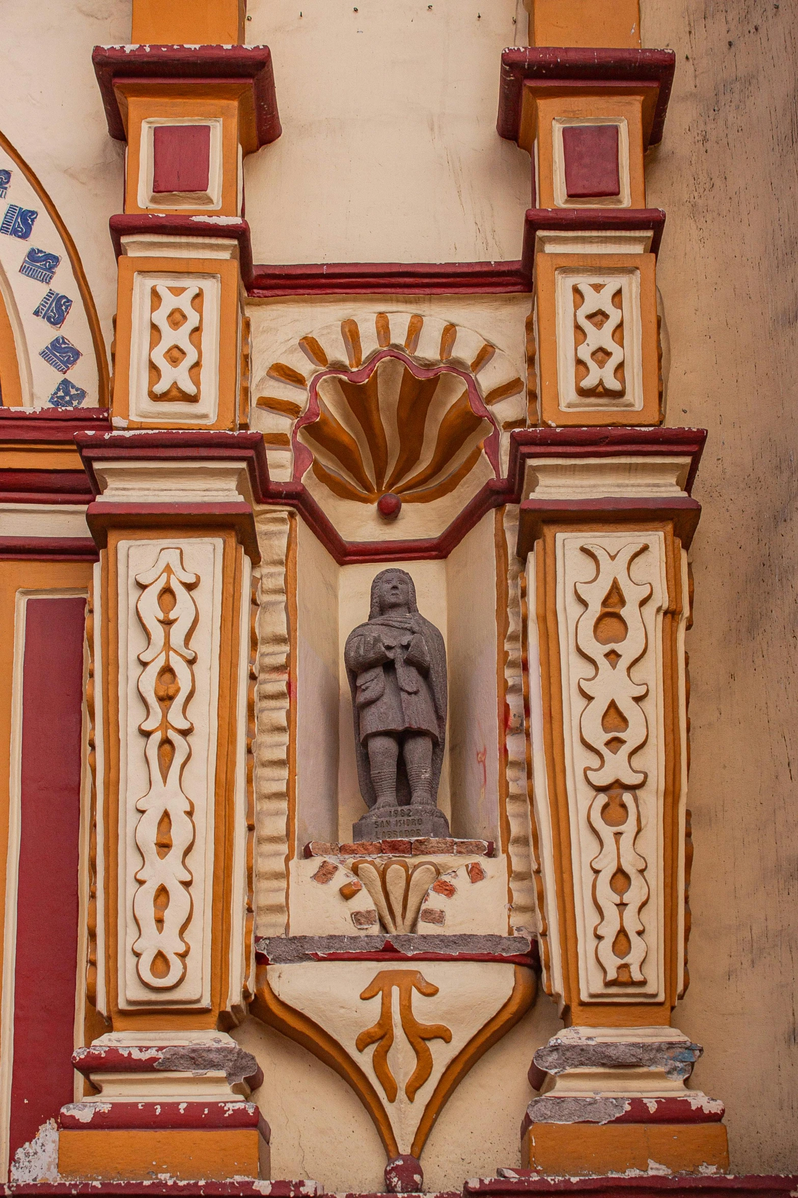 an old building's colorful wall has a statue on it