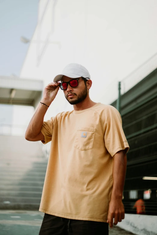 a man standing wearing sunglasses, and a hat