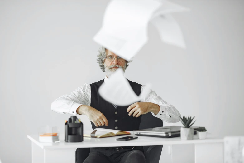 a man sitting at a desk with a white paper covering him