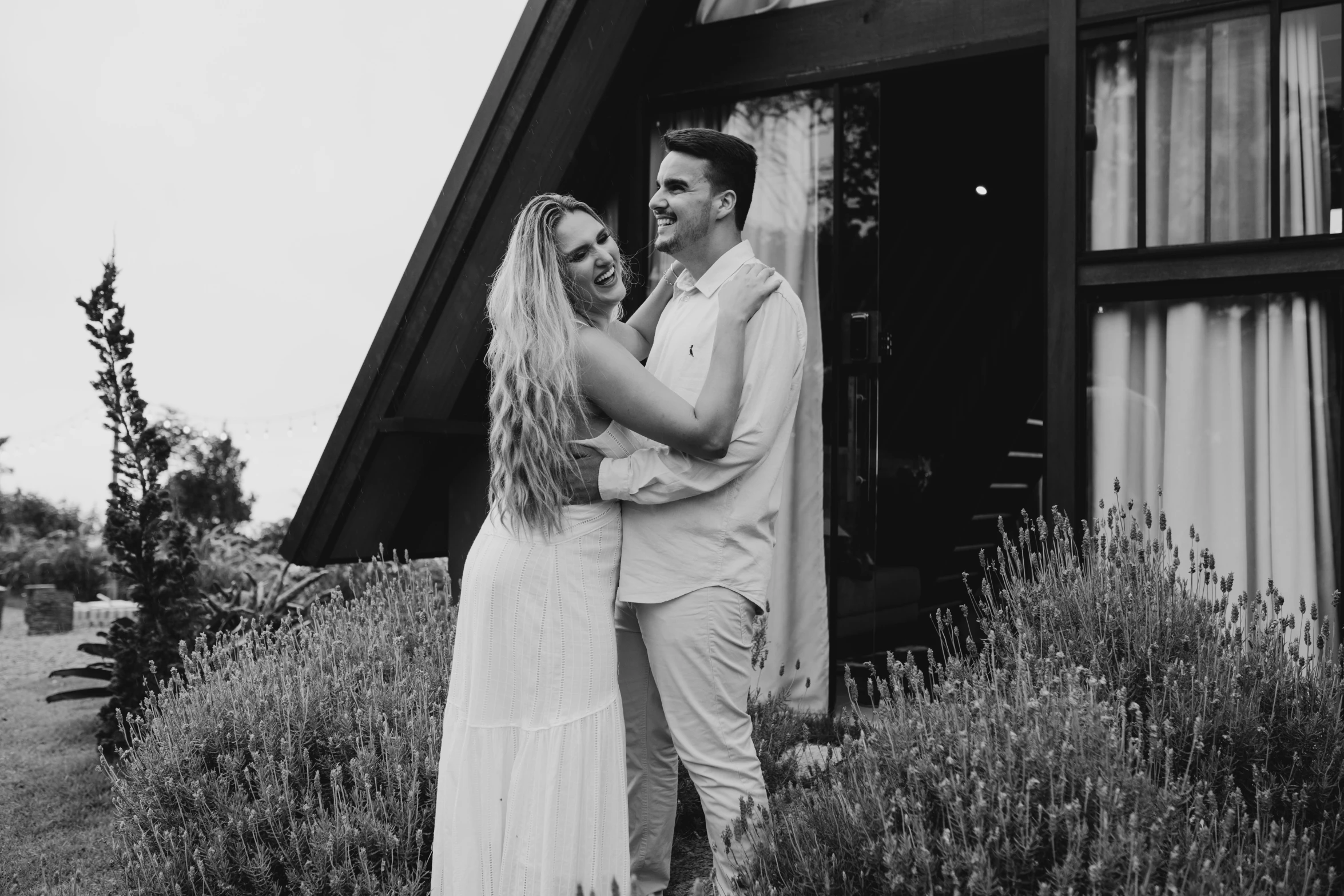 a couple standing outside of a home hugging