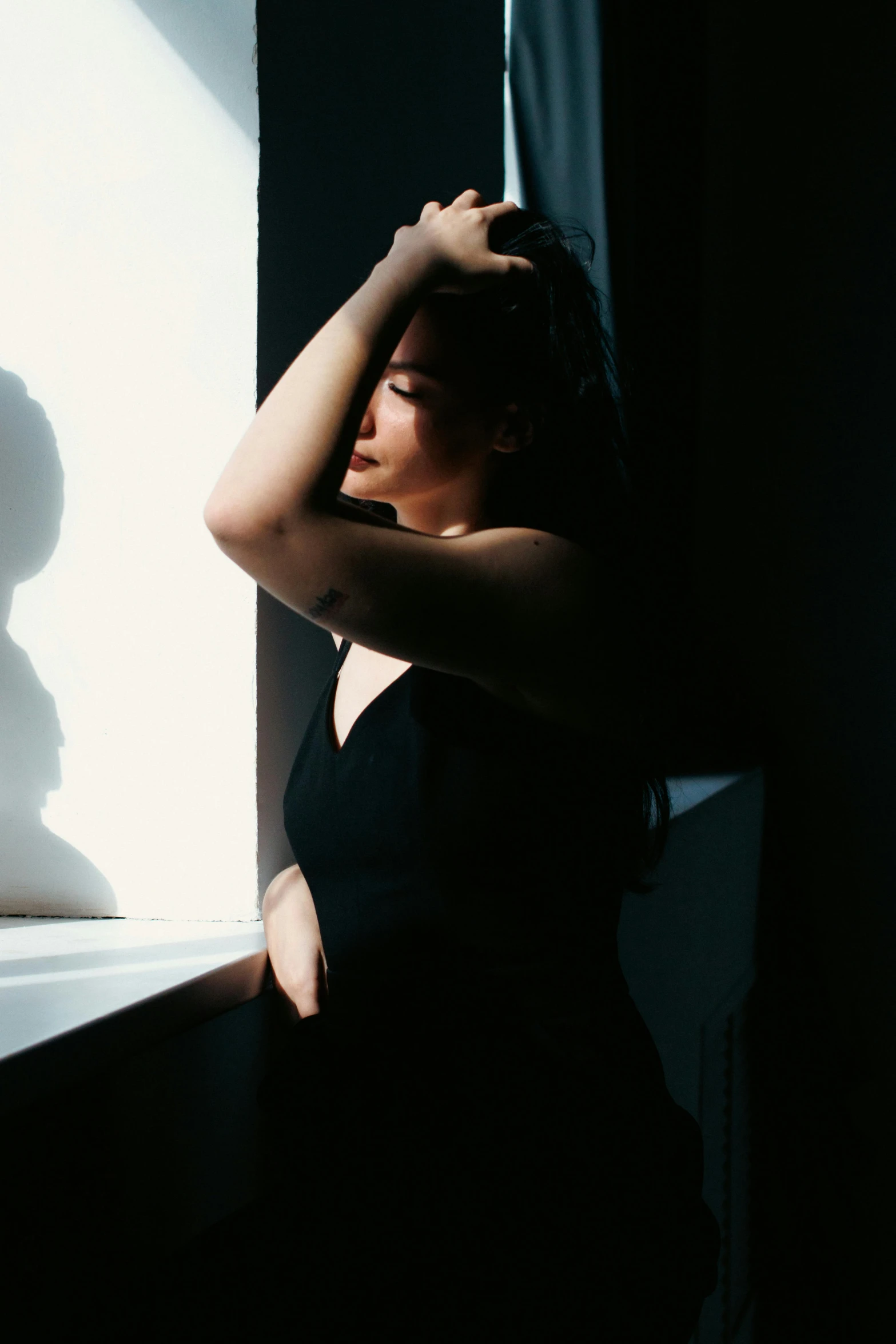 a person leaning against a window in a dark room