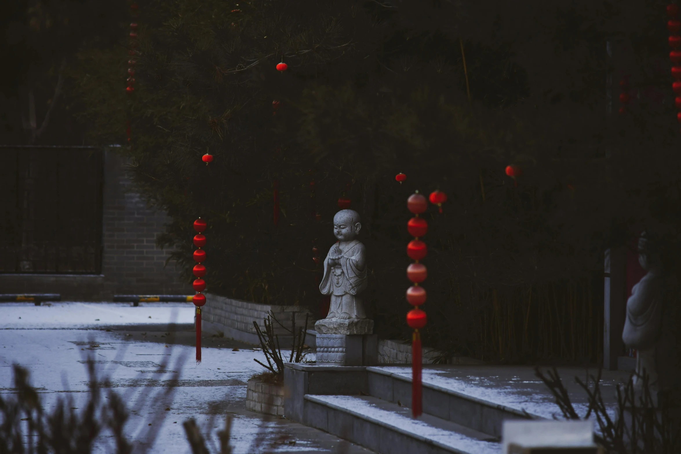 a small white statue sitting in the snow next to tall red candles